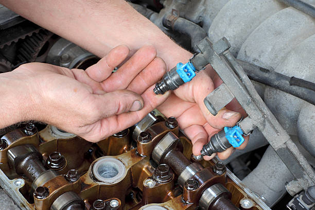 Car mechanic fixing fuel injector at  two camshaft gasoline engine
