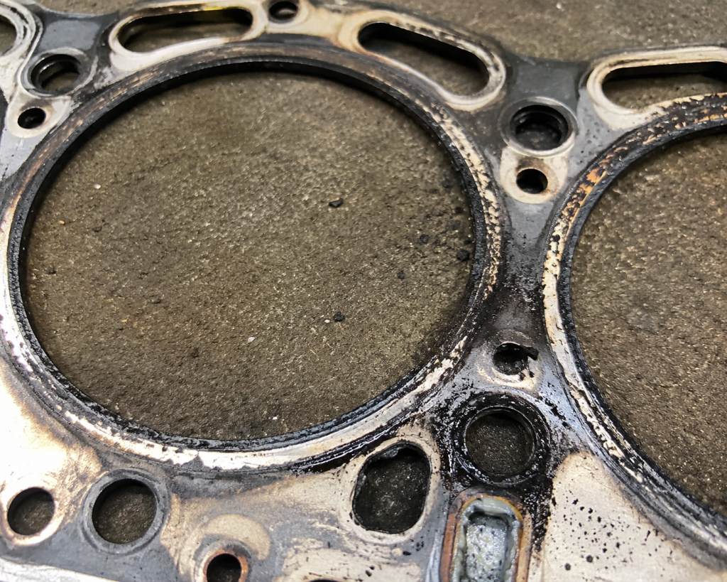 Blown Cummins head gasket showing burn marks and coolant leaks